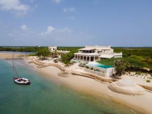 a house on a beach with a boat in the water at Amani House 5 bedrooms sleeps 10 in Shela