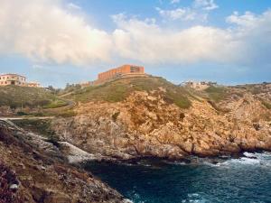 een gebouw bovenop een heuvel naast de oceaan bij Zeeva Hotel and Resort in Torre Dei Corsari