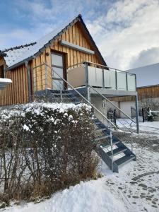 a cabin in the winter with snow on the ground at Ferienwohnung am Kalten Bach in Dürrröhrsdorf