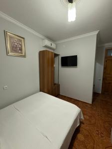 a bedroom with a white bed and a flat screen tv at Nika house in Ureki