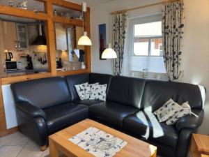 a living room with a black leather couch and a table at gemütliche Doppelhaushälfte in Burhave in Burhave