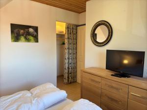 a bedroom with a flat screen tv on a wooden dresser at gemütliche Doppelhaushälfte in Burhave in Burhave