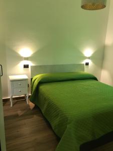a bedroom with a green bed and a white table at A'nicaredda (la piccolina) in Castellammare del Golfo
