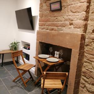 a dining room with a table and chairs and a stone fireplace at The Burrow in Penrith +7 photos