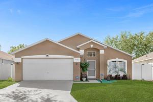 een huis met een witte garage in een tuin bij 1st Animatronic Dinosaur Villa in Orlando