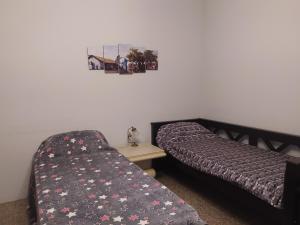 a bedroom with two beds and a table and a picture on the wall at Divertido y Cómodo in Villa Ballester
