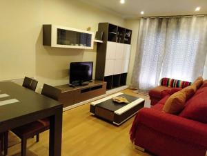 ein Wohnzimmer mit einem roten Sofa und einem Fernseher in der Unterkunft Barraña Boiro Mar in Boiro