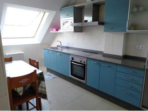 eine Küche mit blauen Schränken, einem Waschbecken und einem Tisch in der Unterkunft Barraña Boiro Mar in Boiro