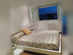 ein kleines Schlafzimmer mit einem Bett mit Fenster in der Unterkunft Barraña Boiro Mar in Boiro