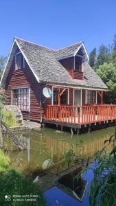 a log house with a deck on the water at Cabaña el rincón in Puerto Montt