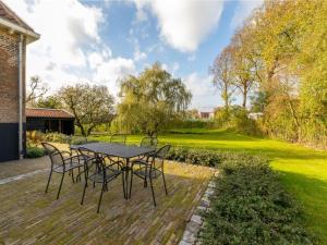 a table and chairs on a patio with a lawn at Farmhouse in Zeeland with Windmill Views in Heinkensand