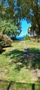 a yard with a house and trees and the ocean at Cabaña el rincón in Puerto Montt