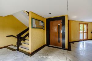 einen Flur mit Tür und Treppe in einem Haus in der Unterkunft Unidades em Prédio com Piscina em Gramado - MDC in Gramado