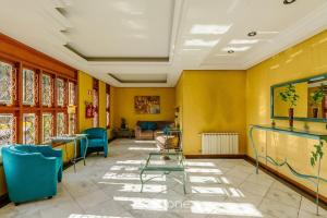 ein Wartezimmer mit gelben Wänden und blauen Stühlen in der Unterkunft Unidades em Prédio com Piscina em Gramado - MDC in Gramado