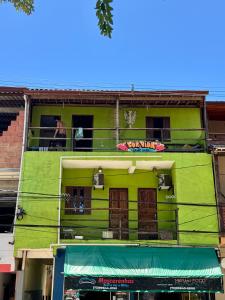 a lime green building with a balcony at Casa Boa Vida GuestHouse in Itacaré