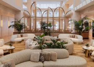 a lobby with white couches and tables and plants at Regent Santa Monica Beach by IHG in Los Angeles