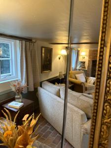 ein Wohnzimmer mit einer Couch und einem Spiegel in der Unterkunft Mantlemas Cottage in Turners Hill