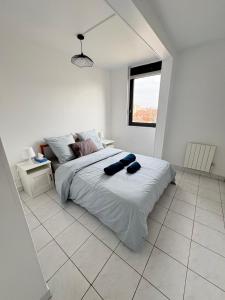a white bedroom with a large bed and a window at F3 avec Projecteur à 2 min du métro in Saint-Ouen
