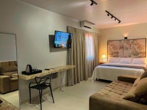 a bedroom with a bed and a desk and a couch at Hotel Flor de Lis in Brejo Santo