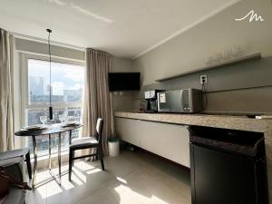 a room with a kitchen with a microwave and a table at Lindos Flats Studios no Qualité in Tambaú