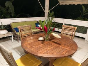 a wooden table with chairs and a vase of flowers at La Siguine in Gourbeyre