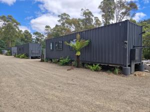 a row of black shipping containers on a dirt road at Rail Trail Retreat in Scottsdale