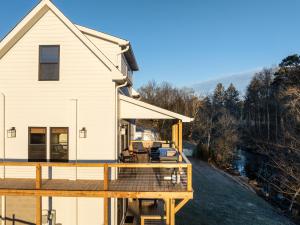 a house with a large wooden deck next to a river at Riverfront Fishing, Firepit, Only 4 Miles to the Speedway in Bluff City