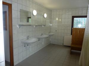 a bathroom with two sinks and two mirrors at Hostel Le Chandelier in Saint-Ursanne