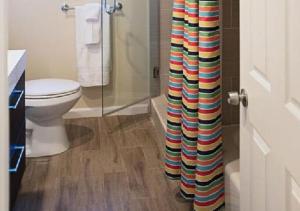 a bathroom with a toilet and a colorful shower curtain at MagicwayVillas Paradise Pier Home - Across Disney in Anaheim +12 photos