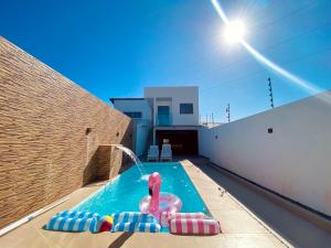 Una piscina con un juguete rosa en una casa. en Bela acomodação em jacuipe com churrasqueira, piscina, mesa de sinuca e três quartos, dois sendo suítes! Além de muito espaço por toda a área!, en Barra do Jacuípe