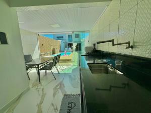 Una cocina con una mesa y un comedor. en Bela acomodação em jacuipe com churrasqueira, piscina, mesa de sinuca e três quartos, dois sendo suítes! Além de muito espaço por toda a área!, en Barra do Jacuípe