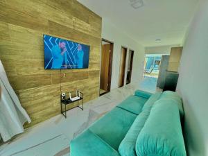 Una sala de estar con un sofá azul y un televisor de pantalla plana. en Bela acomodação em jacuipe com churrasqueira, piscina, mesa de sinuca e três quartos, dois sendo suítes! Além de muito espaço por toda a área!, en Barra do Jacuípe