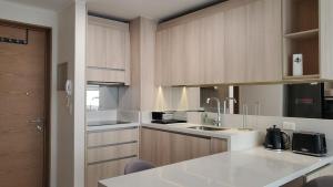 une cuisine avec un comptoir blanc et des placards en bois dans l'établissement Modern Apartamento con Suites - Centro de Temuco, à Temuco