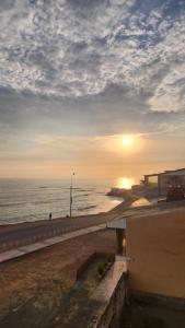 a sunset on a beach with the ocean and a building at Macky'sThe Silence in Bombiso