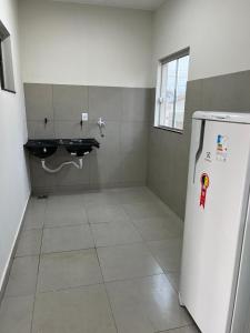 a room with a refrigerator with a sink in it at Residencial Mangueiral in Paracatu