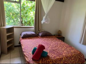 a bedroom with a bed with two pillows and a window at Maupiti Vaitia Lodge in Maupiti