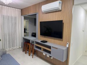 een woonkamer met een flatscreen-tv aan de muur bij Lazer completo e vista inesquecível in Guarujá