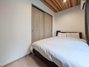 a bedroom with a white bed and a wooden door at THE TERRAce HAKATA in Fukuoka