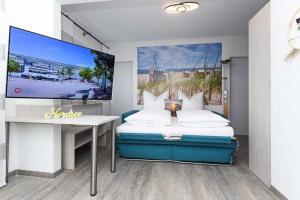 Un dormitorio con una cama, un escritorio y un televisor. en Strandkorb 4, en Bensersiel
