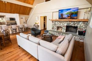 a living room with a couch and a stone fireplace at Stunning secluded Creekside A-Frame gameroom in Lake Arrowhead