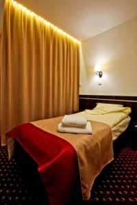 a hotel room with a bed with two towels on it at Hotel Milord in Pułtusk