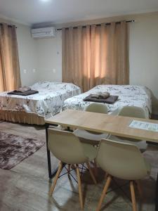 a room with two beds and a table and chairs at Loft Confort in Pomerode