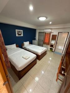 Un dormitorio con dos camas y una pared azul. en Wellington Apartment, en Ban Nong Waeng