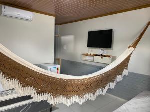 a hammock in a living room with a tv at POUSADA SOL e LUAR in Santo Amaro