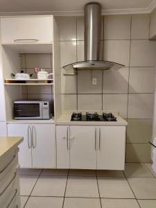una cocina con estufa y microondas en Apê Suíça Baiana, en Vitória da Conquista