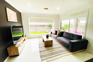 Una sala de estar con un sofá y un televisor de pantalla plana. en Kellyville 5Br Near park and shopping mall, en Kellyville