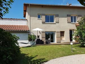 a house with an umbrella in the yard at Charmant Gîte dans les Monts du Lyonnais avec Jardin, Terrasse et Confort Moderne - FR-1-496-174 in Maringes