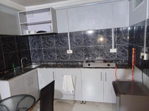 イバダンにあるBudget one bedroom apartmentの黒いタイル張りの壁、白いキャビネット付きのキッチン +11枚の写真
