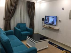 a waiting room with blue chairs and a tv at Pyramiza Hotel Al Mangaf فندق بيراميـــزا المنقف in Kuwait