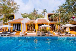 a resort with a swimming pool with chairs and umbrellas at Hoi An Phu Quoc Resort & Spa in Phu Quoc +35 photos